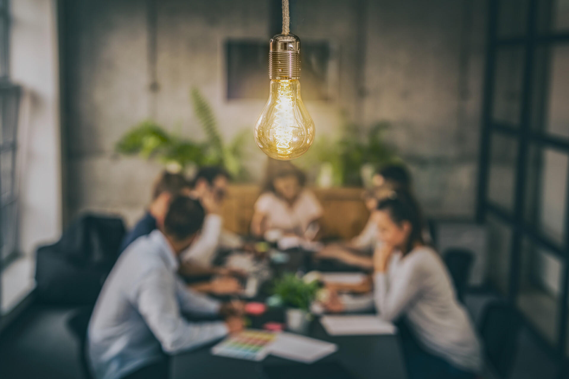 Young creative business people meeting at office. Young business people are discussing together a new startup project. A glowing light bulb as a new idea.